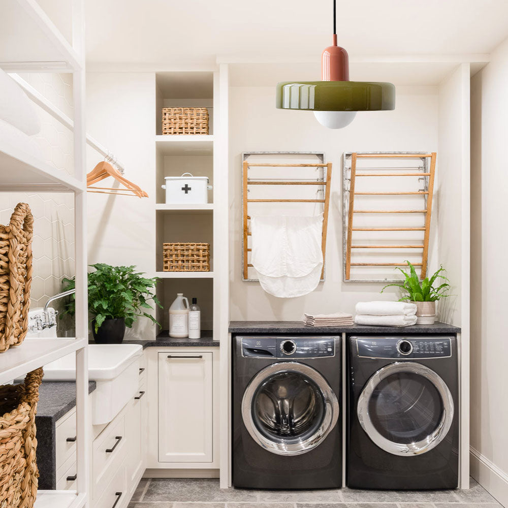 Olive glass pendant light lighting a white laundry room with drying racks