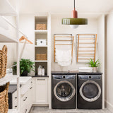 Olive glass pendant light lighting a white laundry room with drying racks