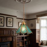 Blue panelled glass pendant with a scalloped brass frame lit in a panelled room