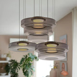 Cluster of smoke grey mixed-layer glass pendant lights in a bright plant-filled room