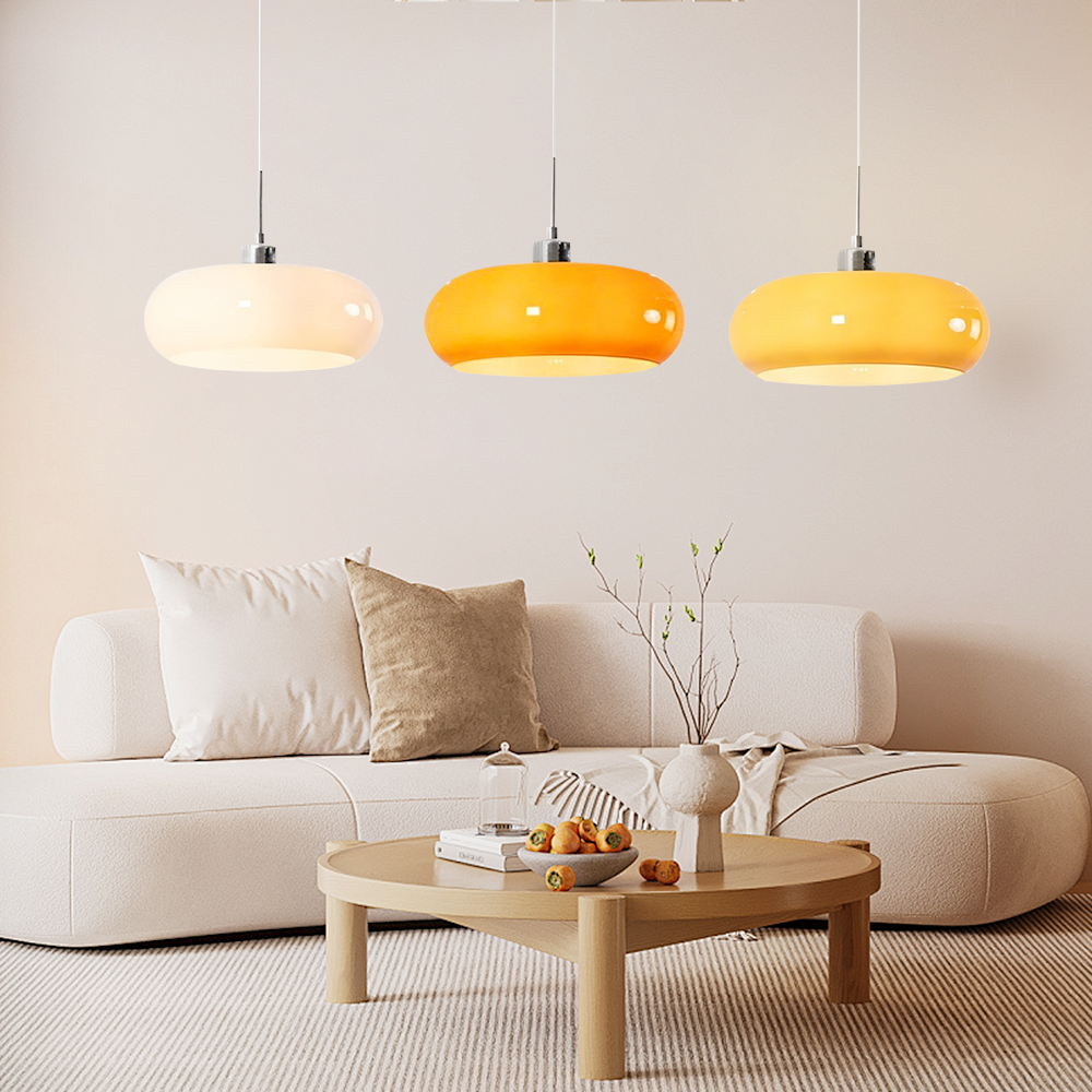 Three glass pendant shades in white, orange and yellow above a sofa