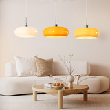 White, orange, and yellow glass pendant light trio over a sofa