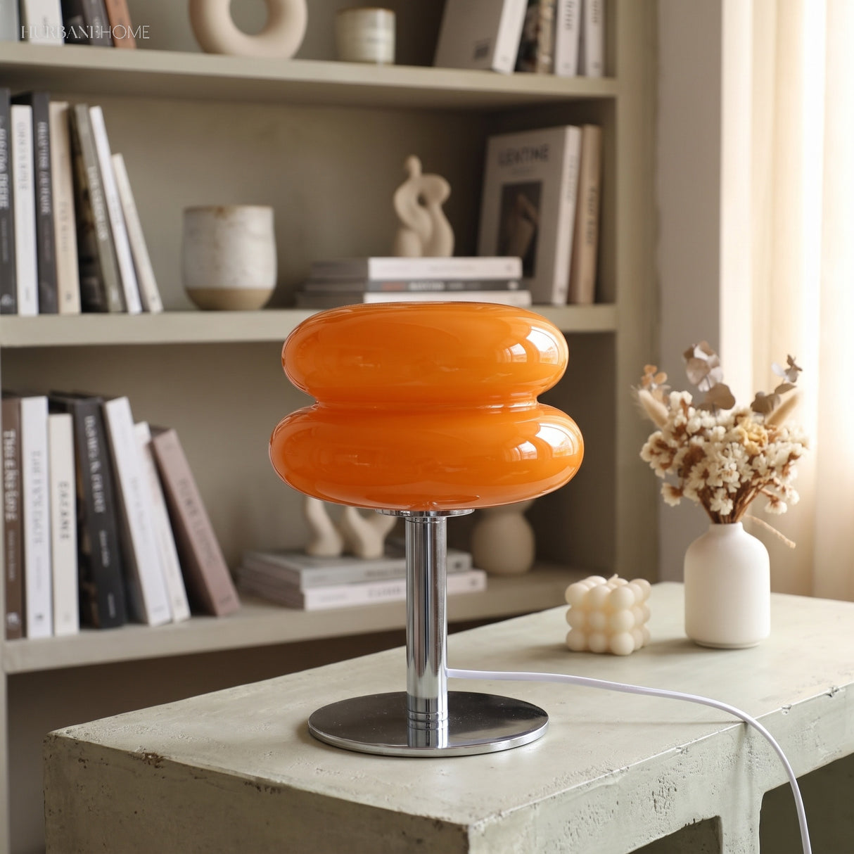 Orange glass lamp glowing on a concrete plinth in front of shelves