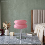 Pink stacked glass lamp lit on a stone counter in a green room