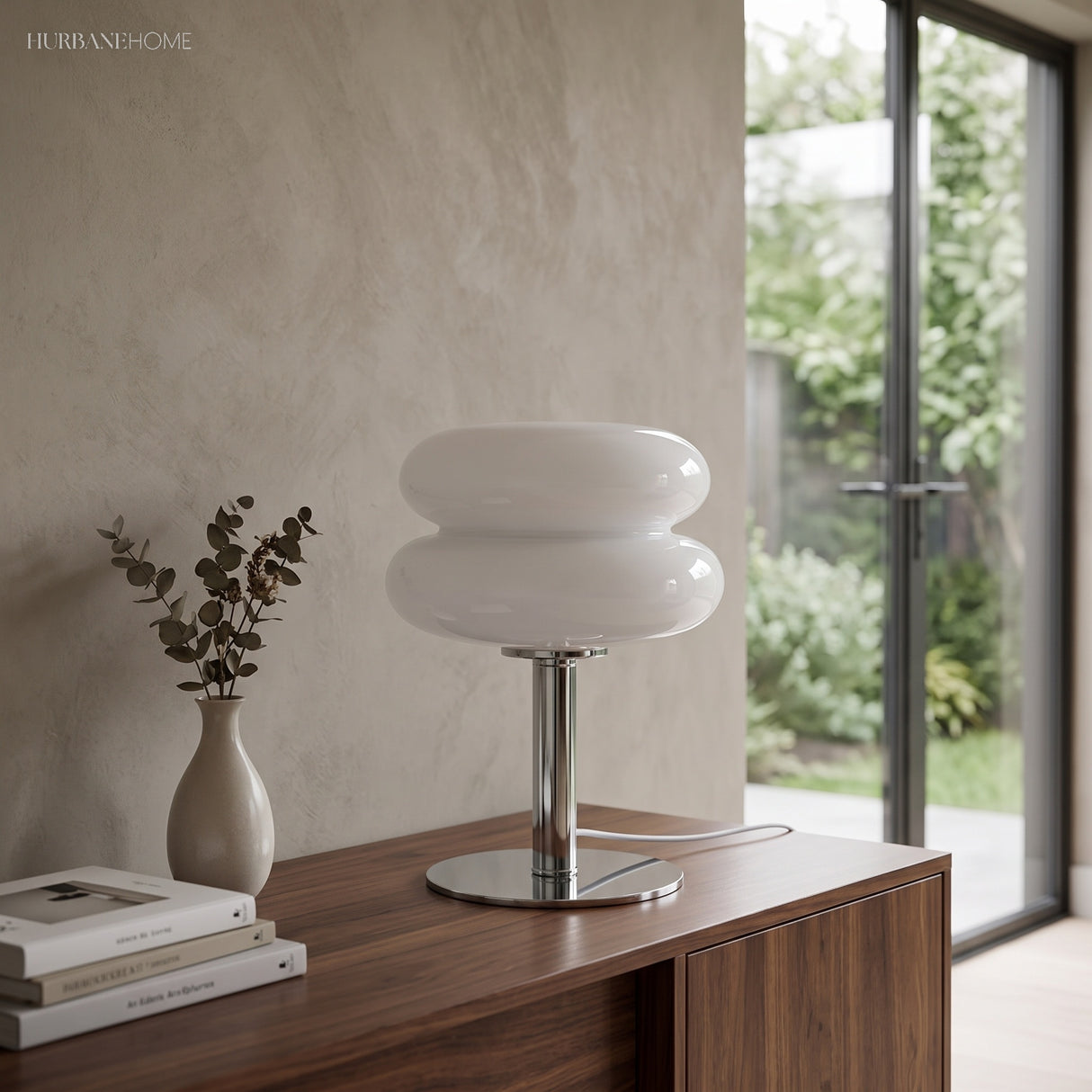 White stacked glass lamp lit on a console table beside a doorway