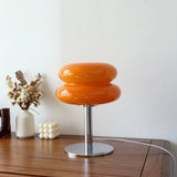 Orange two tier glass lamp lit beside dried flowers on a sideboard