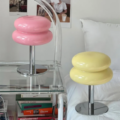 Pink and yellow glass lamps beside a clear chair and stacked books