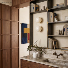Pair of glass wall sconces on a cream study wall with marble counter