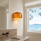 Glass wall sconce close-up showing the glossy tinted upper dome