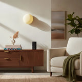 Glowing glass wall sconce above walnut sideboard in modern living room