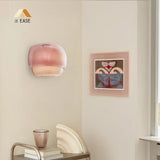 Lit glass wall sconce casting a warm downward glow in a styled room