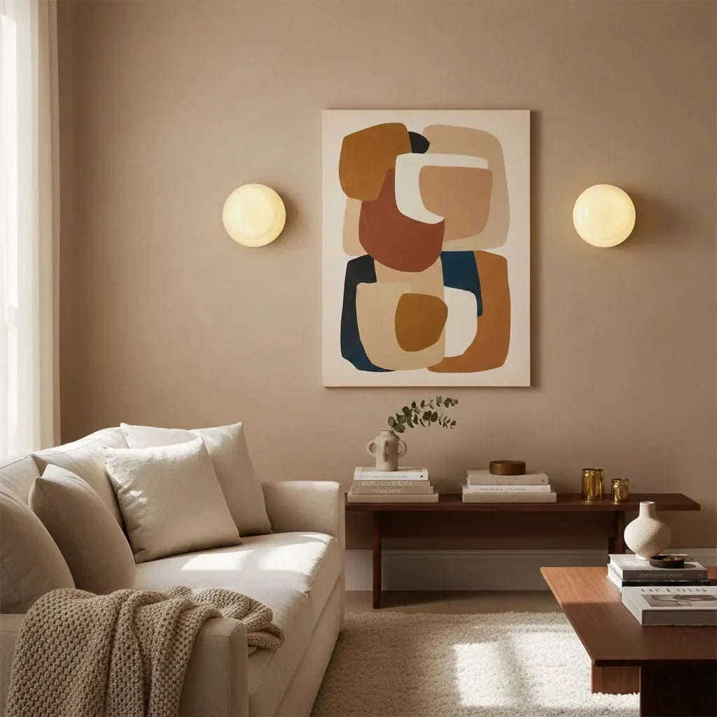 Pair of glass wall sconces flanking abstract art in neutral lounge