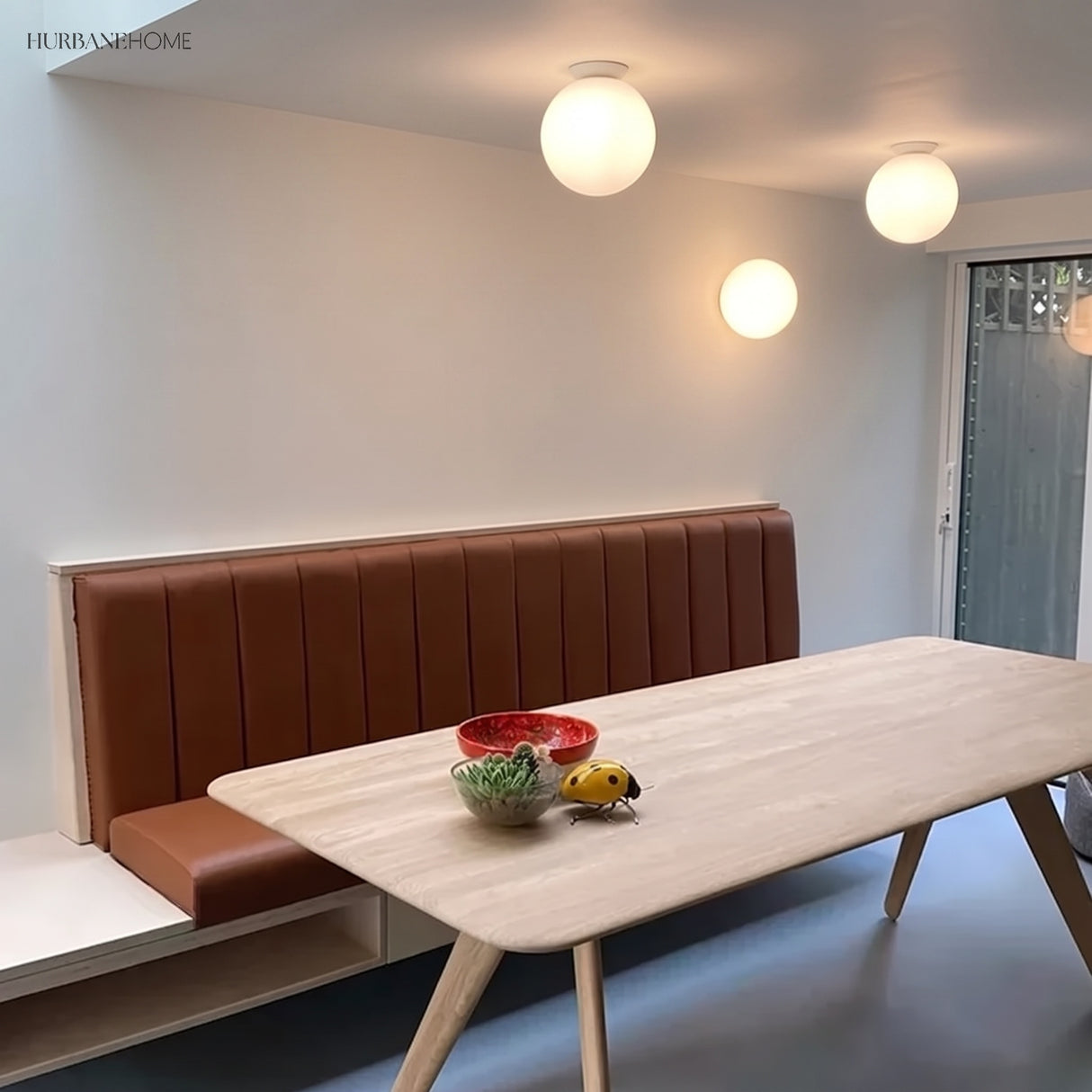 Glass globe ceiling lights above a dining table and leather banquette