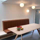 Glass globe ceiling lights above a dining table and leather banquette
