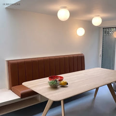Glass globe ceiling lights above a dining table and leather banquette