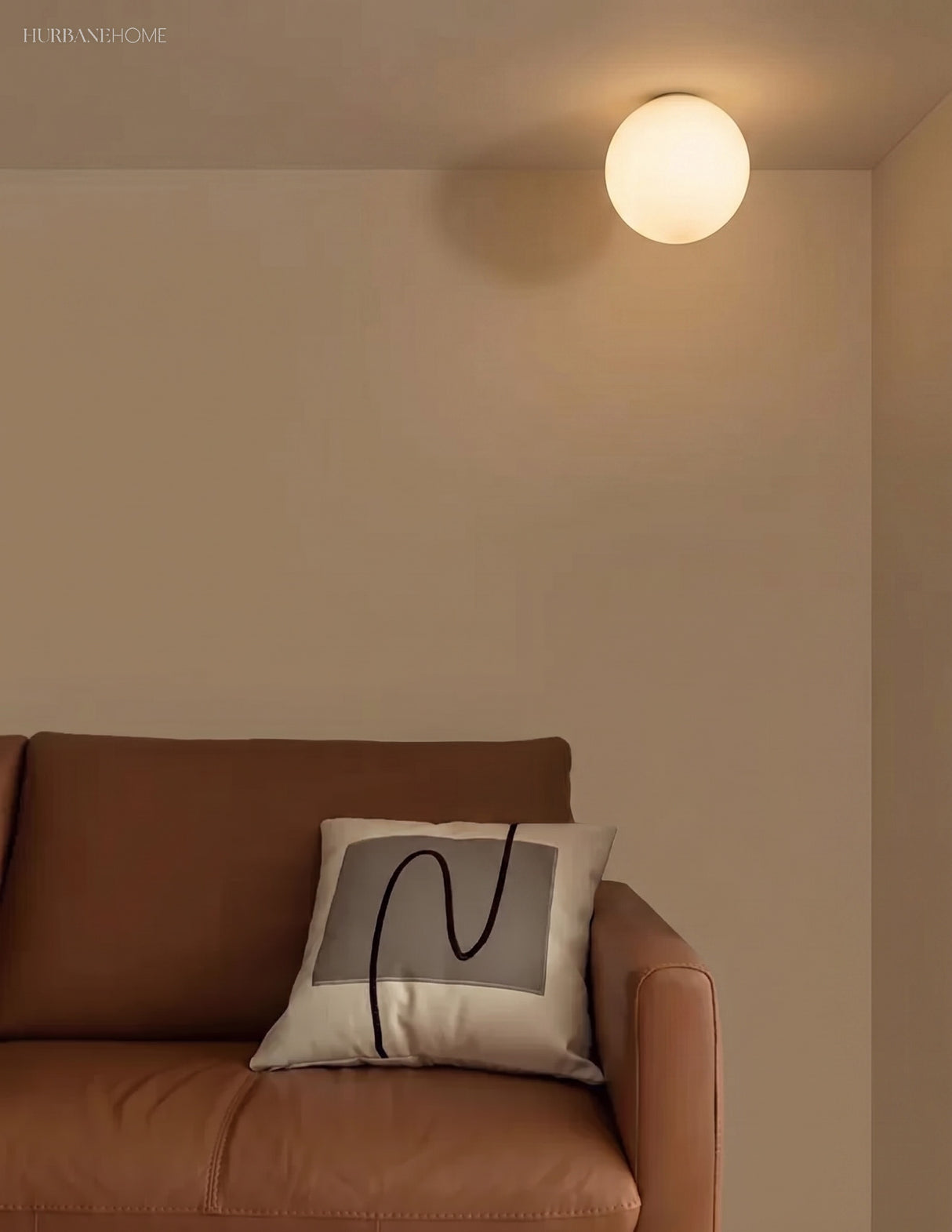 Glass globe light in a living room corner above a tan leather sofa