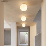 Three glass globe ceiling lights along a plastered corridor ceiling