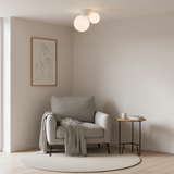 Twin globe ceiling light above a reading corner with a grey armchair