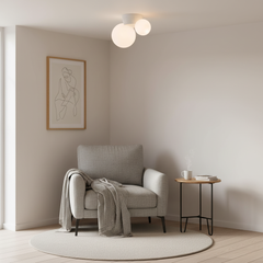 Twin globe ceiling light above a reading corner with a grey armchair