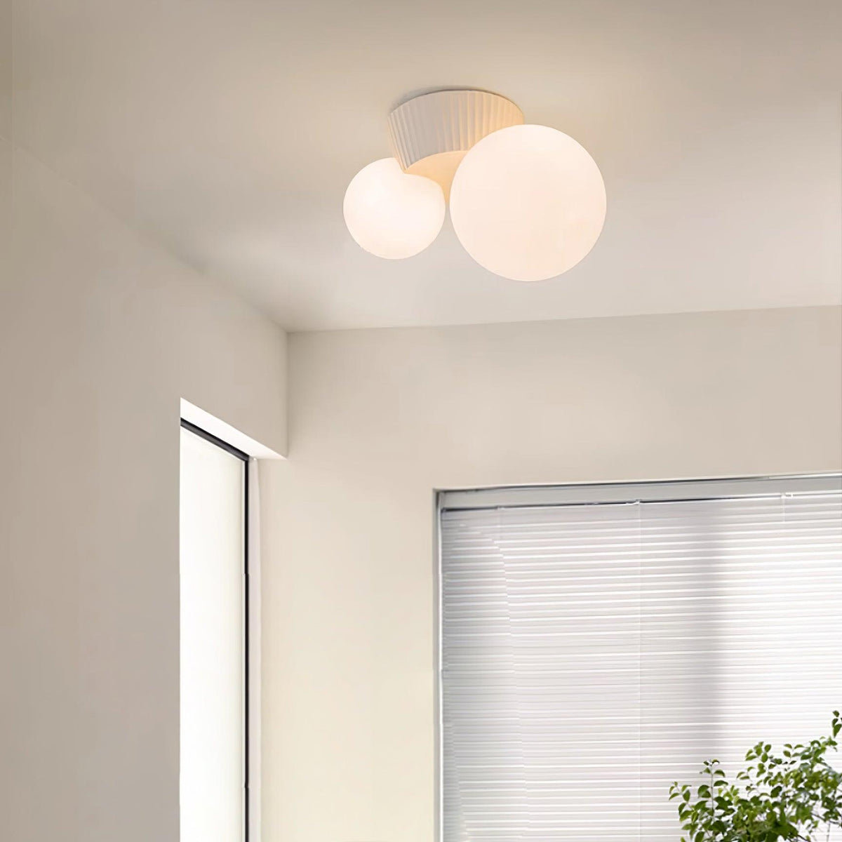 Twin globe ceiling light close to a window corner with a plant below