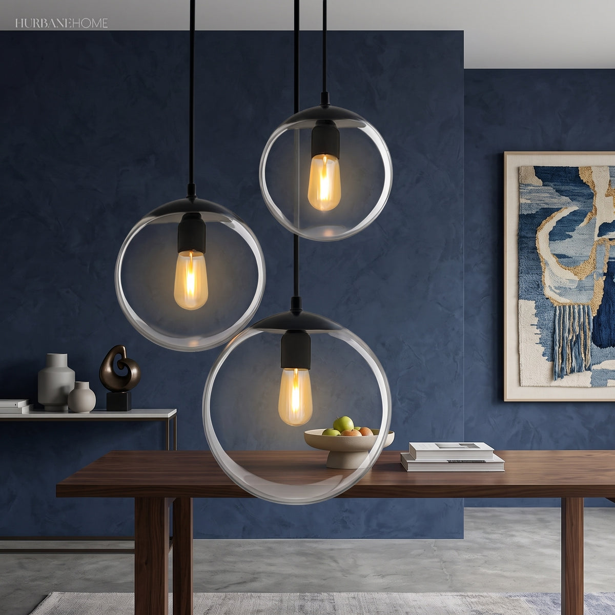 Three glass globe pendants lit above a table on a blue wall