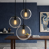 Three glass globe pendants lit above a table on a blue wall