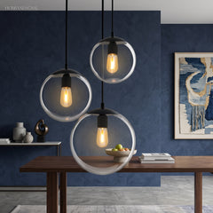 Three glass globe pendants lit above a table on a blue wall