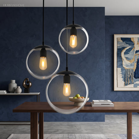 Three glass globe pendants lit above a table on a blue wall