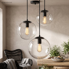 Two glass globe pendants lit above a dining table and rattan chair