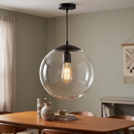 Clear glass globe pendant lit above a timber dining table