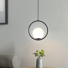 Black round hoop pendant lit above a table with a small vase
