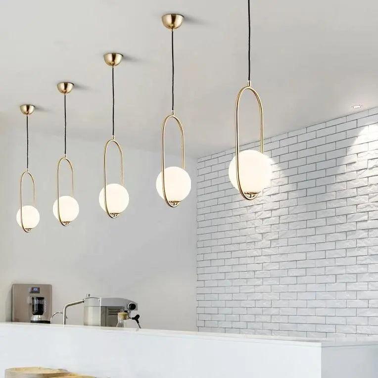 Gold hoop pendants in a row along a white brick kitchen wall