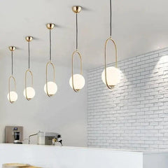 Gold hoop pendants in a row along a white brick kitchen wall