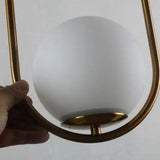 Close view of the brass hoop frame cradling the opal glass globe