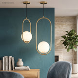 Two gold hoop pendants with glass globes above a dining table