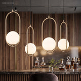 Row of gold hoop pendants lit above a dark marble kitchen counter