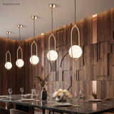 Gold globe pendants in a line above a marble dining table