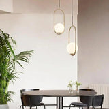 Gold and black hoop pendants above a round dining table with plants