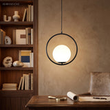 Black round hoop pendant with a glowing globe above a wood desk