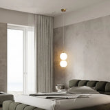 Single globe pendant lit in a pale bedroom beside a balcony door