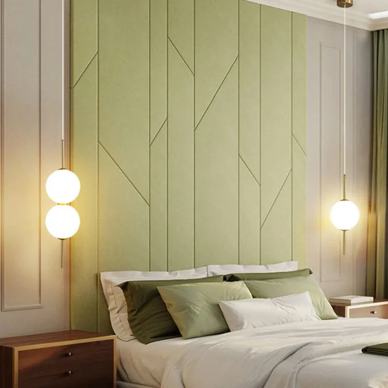 Two globe pendants hung either side of a bed with green panelling