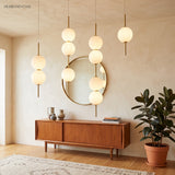 Cluster of globe pendants at mixed heights above a walnut sideboard