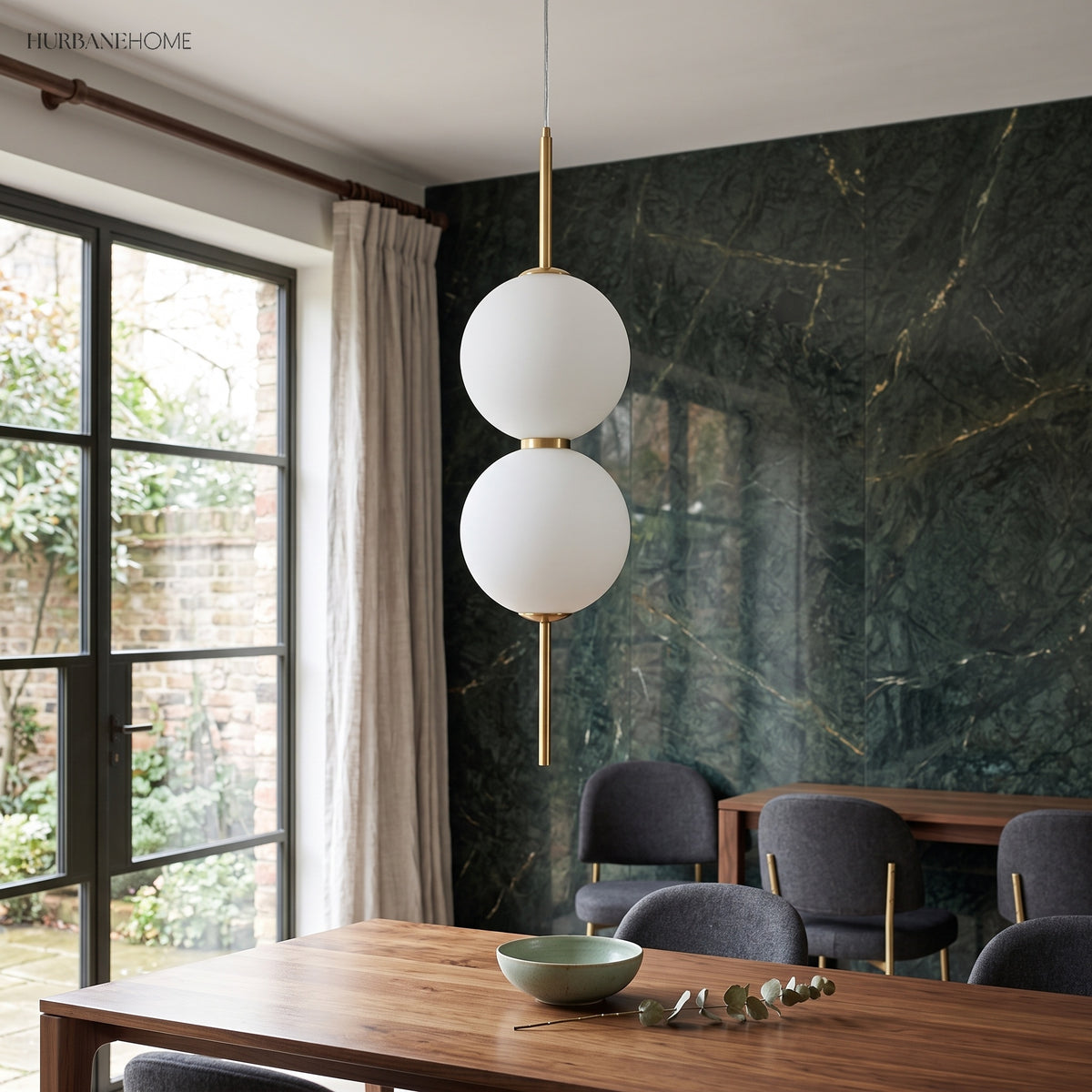 Two stacked glass globes lit beside a window and green marble wall