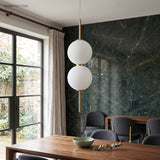 Two stacked glass globes lit beside a window and green marble wall