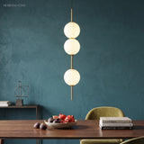 Three opal globes on a brass rod above a dining table and fruit bowl