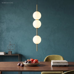 Three opal globes on a brass rod above a dining table and fruit bowl
