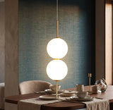 Two opal glass globes on a brass rod above a set dining table