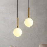 Two globe pendants lit warmly at different heights on a grey wall