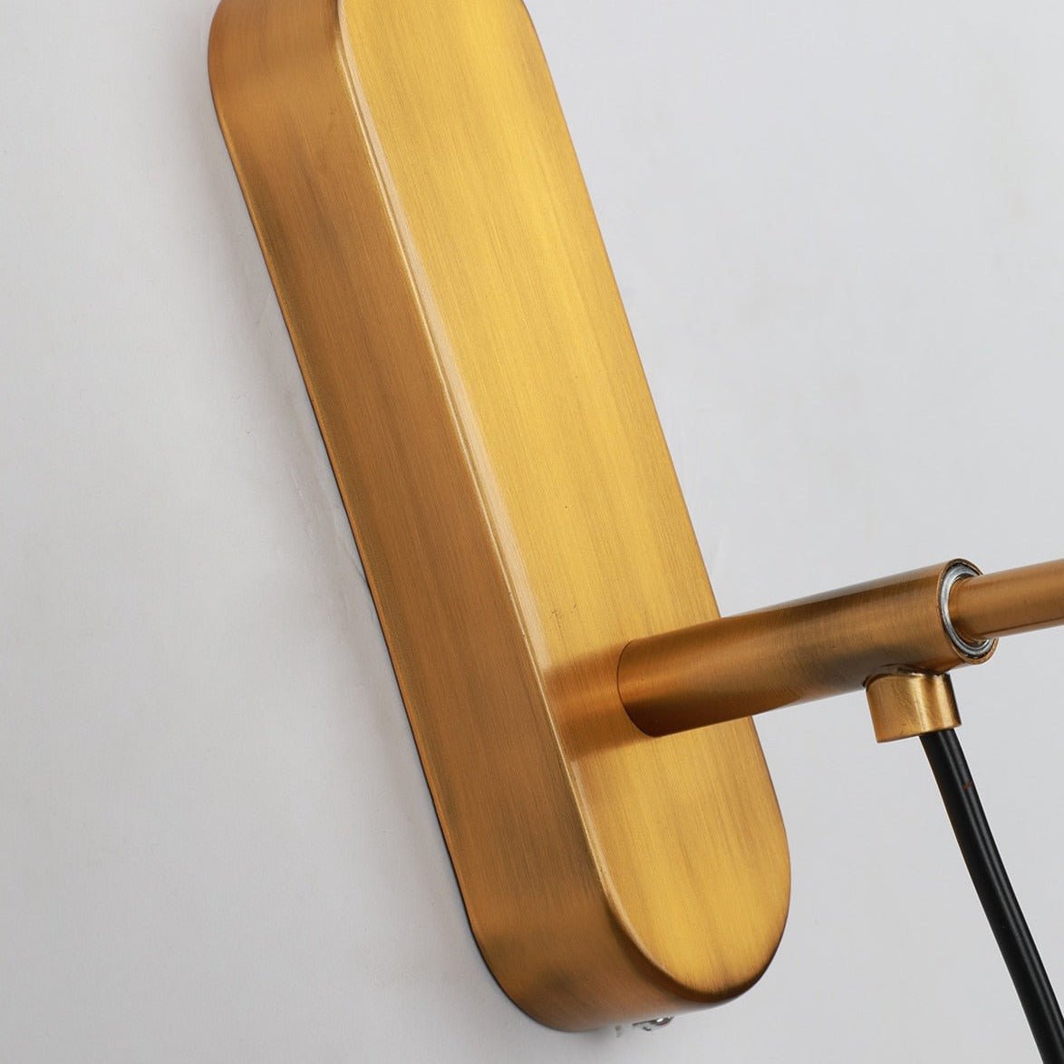 Close view of the rounded brass backplate and the arm joint