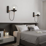 Two black globe wall sconces lit either side of a grey bed